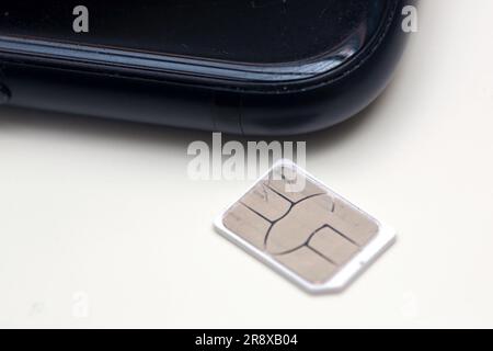 Berlin, Deutschland. 22. Juni 2023. Eine SIM-Karte liegt auf einem Tisch neben einem Smartphone. Kredit: Fernando Gutierrez-Juarez/dpa/Alamy Live News Stockfoto