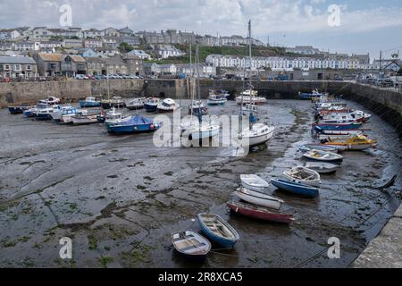 Blick auf den Hafen von Porthleven in Cornwall, England, mit Fischerbooten bei Ebbe. Stockfoto