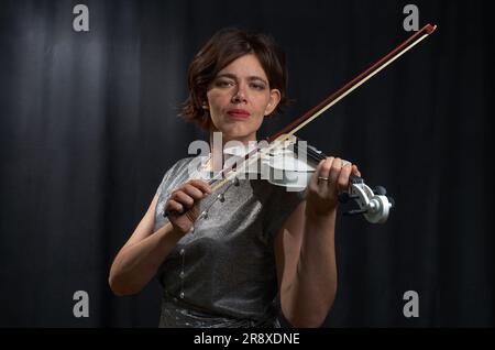 Ein halblanges Porträt einer Frau, die Geige spielt, auf schwarzem Hintergrund Stockfoto