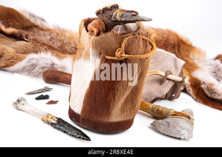 Steinzeit-Handtasche mit Cavemen Ax, Werkzeug und Messer auf weißem Hintergrund Stockfoto