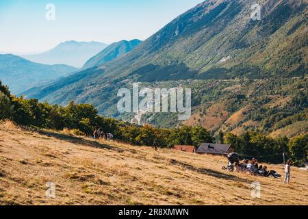 An einem sonnigen Sommerwochenende in Prevalla, einer Bergstadt im Kosovo, entspannen sich die Menschen auf den grasbedeckten Hängen des Prevalla Field Stockfoto