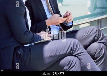 Kollegen, die ihr Smartphone während einer Arbeitspause außerhalb des Büros verwenden Stockfoto