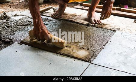 Ein männlicher Bauarbeiter installiert eine große Keramikfliese Stockfoto