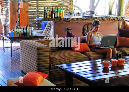 Frau sitzt in öffentlichen Bereichen, Jaci's Tree Lodge, Madikwe Game Reserve, Nordwesten, Südafrika Stockfoto