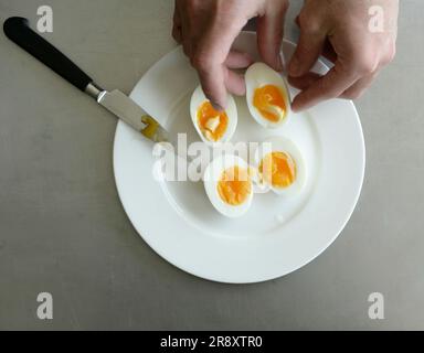 Hartgekochte Eier werden in zwei Hälften geteilt, um ein Dotterchen zu enthüllen. Stockfoto
