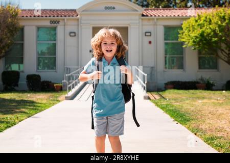 Kinderhündchen mit Rucksäcken im Park in der Nähe der Schule. Schuljunge mit Rucksäcken im Freien. Wissenstag. Schuluniform Stockfoto