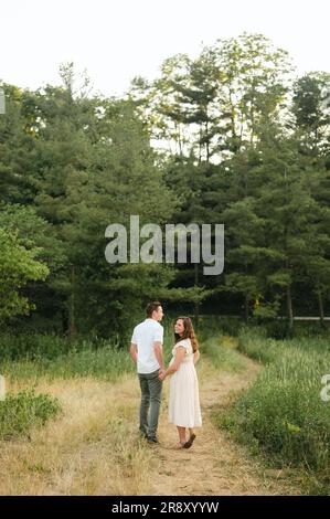 Glücklicher Ehemann und schwangere Frau, die in den Wald gehen Stockfoto