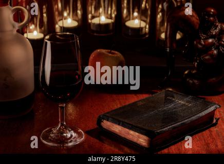 Eine Nahaufnahme der Bibel neben einem Weinglas, eine Interpretation des Priesterstudiums Stockfoto
