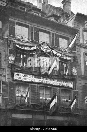 "Petain et Foch a Strasbourg; La parure de Fete de Strasbourg liberee: deux Facades ornees sur la Grande-Rue et sur le quai des Bateliers. Le soleil, qui avait rayonne le 22 novembre, pour l'entr&#xe9;e de Gouraud et de ses braves, manquait a la journee du 25. Mais l'Exaltation de la Population sut donner a la Fete de ce jour-la un caractere qui atteignit au Sublime',1918. Aus „L'Album de la Guerre 1914-1919, Band 2“ [L'Illustration, Paris, 1924]. Stockfoto