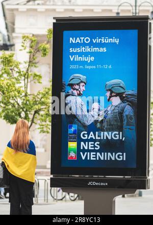 Werbebanner, das über den bevorstehenden NATO-Gipfel 2023 im Zentrum von Vilnius, der Hauptstadt Litauens, informiert, mit einem Mädchen mit der Flagge der Ukraine, die läuft Stockfoto