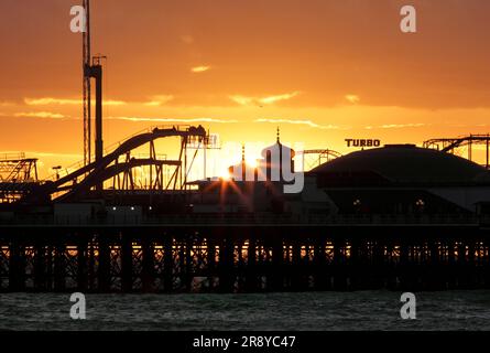 Die Abendsonne sinkt hinter zwei Zwiebelkuppeln am Ende von Brighton's Palace Pier. Stockfoto