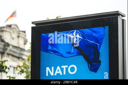 Werbebanner, das über den bevorstehenden NATO-Gipfel 2023 im Zentrum von Vilnius, der Hauptstadt Litauens, informiert, mit litauischer Flagge im Hintergrund Stockfoto