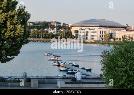 Kasan, Russland - 7. Juni 2023: Städtische Sommerlandschaft. Blick auf den Nizhny Kaban See vom Ufer. Menschen, die Katamarane fahren. Stockfoto