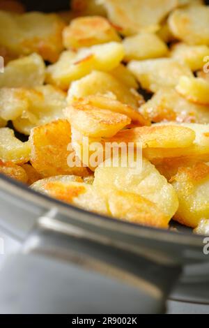 Eine kleine Portion gebratener oder gebackener gelber Kartoffeln mit knuspriger brauner Kruste in einer Pfanne. Vertikales Bild mit selektivem Fokus. Stockfoto