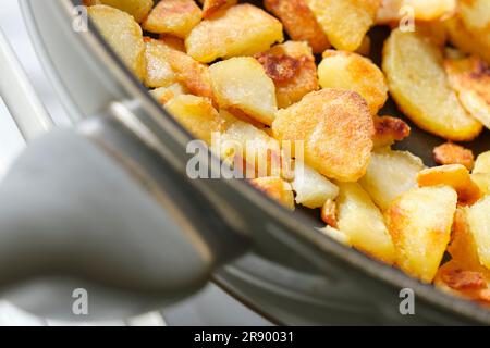 Eine kleine Portion gebratener oder gebackener gelber Kartoffeln mit knuspriger brauner Kruste in einer Pfanne. Bild mit selektivem Fokus. Stockfoto