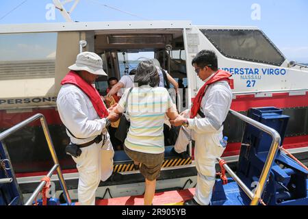 Zwei philippinische Seeleute helfen einem Passagier des Kreuzfahrtschiffs SUPERSTAR VIRGO ((2023 Resorts World One), an Bord eines Rettungsbootes zu gehen Stockfoto