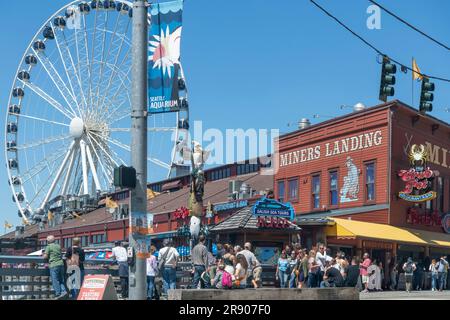 Seattle, WA, USA - Juli 2022; Blick auf die Menschen an einem der Piers der Seattle Waterfront mit Restaurants, Geschäften und Riesenrad Stockfoto