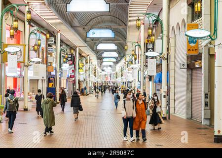 Sehen Sie die geschäftige Fußgängerzone Kyusaigokukaido, eine überdachte Strandarkade im Motomachi-Viertel Kobe am Abend. Stockfoto