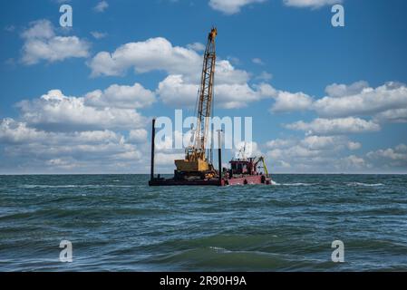 Lastkahn für den Transport großer Felsen zum Bau von Wellenbrechern, um Strände vor Wellen und Gezeiten zu schützen. Stockfoto