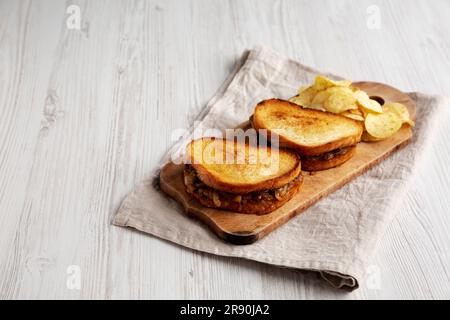 Hausgemachtes französisches Schmelzsandwich mit karamellisierten Zwiebeln und Gruyure-Käse auf einem rustikalen Holzbrett, Seitenblick. Speicherplatz kopieren. Stockfoto