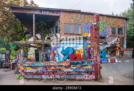 Kopenhagen, Dänemark - 14. September 2010: Christiania freetown. Bunte Graffiti-Kakophonie an Wänden, Säulen und allem. Grünes Laub und graue s. Stockfoto