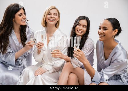 hochzeitsfeier, gemischtrassige Freundinnen, die Gläser mit Champagner halten, Feiern vor der Hochzeit, brünette und blonde Frauen, Braut und ihre Brautjungfern Stockfoto