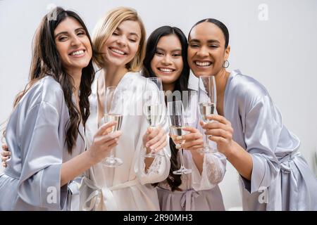 brautdusche, multikulturelle Freundinnen, die Gläser mit Champagner halten, Feier vor der Hochzeit, brünette und blonde Frauen, Braut und ihre Braut Stockfoto