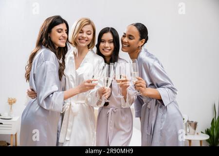 hochzeitsfeier, gemischtrassige Freundinnen, die Gläser mit Champagner halten, Feiern vor der Hochzeit, brünette und blonde Frauen, Braut und ihre Brautjungfern Stockfoto