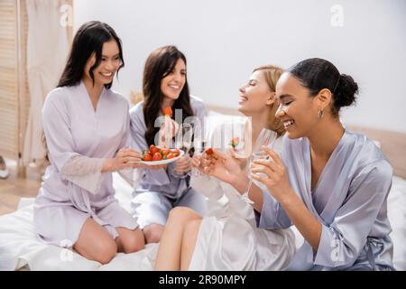 hochzeitsfeier, Erdbeeren und Champagner, vier Frauen, multikulturelle Freundinnen, die Spaß haben, brünett und blond, Braut und Brautjungfern, die Ti ausgeben Stockfoto