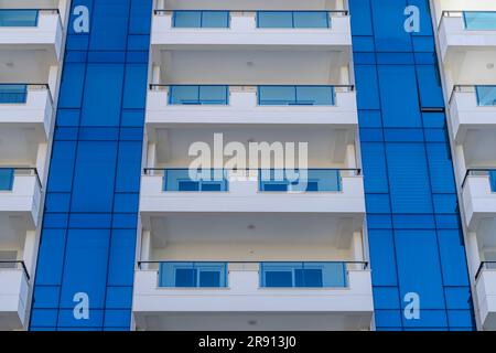 Ein Fragment eines mehrstöckigen Wohngebäudes mit geräumigen Balkonen. Architektonische Details eines modernen Gebäudes. Stockfoto