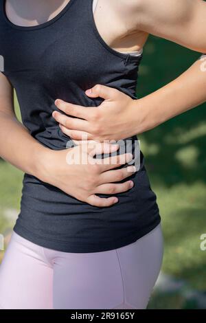 Die Sportlerin hat beim Laufen akute Schmerzen in ihrer Seite. Stockfoto