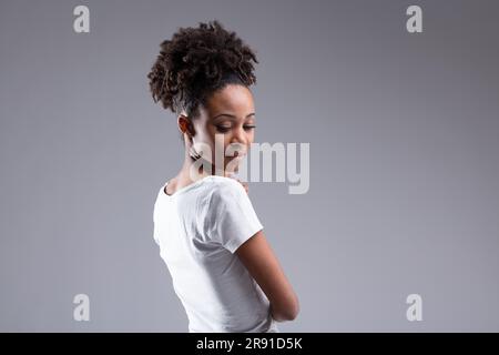 Porträt einer umwerfenden jungen Frau, von hinten gesehen, nach unten gedreht. Aufmerksam, schüchtern, schüchtern? Bescheidenheit vorzutäuschen, wenn man hochmütig ist? Aber es scheint beunruhigt zu sein Stockfoto