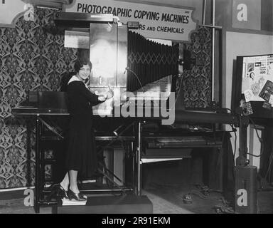New York, New York: c. 1931 Eine junge Frau, die den neuen Rektigraph auf der National Business Show vorführt. Diese Fotomaschine erstellt Aktenkopien von Büromaterial. Stockfoto