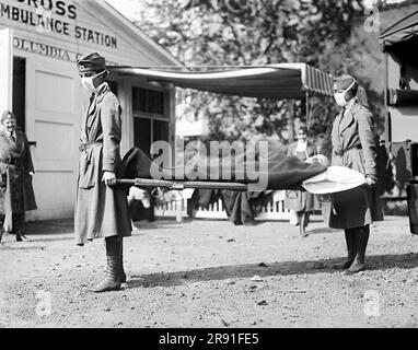 Washington, D.C.: 1918 zwei Rotkreuz-Krankenschwestern mit einer Person auf einer Trage während einer Demonstration in der Rotkreuz-Notarztstation während der Grippepandemie von 1918-1920. Stockfoto