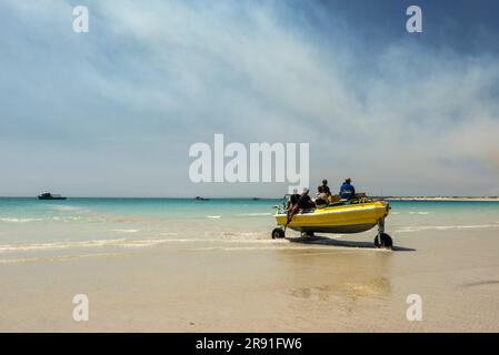 Ein aufblasbares Boot voller Menschen mit Rädern kommt aus dem Wasser auf den Cable Beach in Broome West Australia Stockfoto