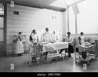 Millport, Schottland: c. 1925 Ein Arzt und seine Krankenschwestern posieren in ihrem neuen hellen Operationssaal in einem Krankenhaus. Stockfoto