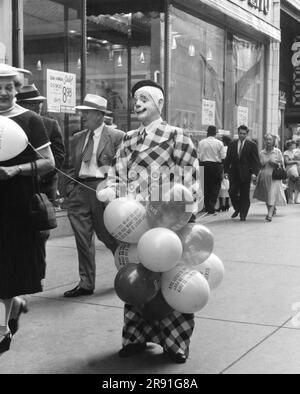 Chicago, Illinois: 11. August 1956, Ein Mann in einem Clownkostüm, der Werbeballons verteilt, die für „State Street Days“ werben. Stockfoto