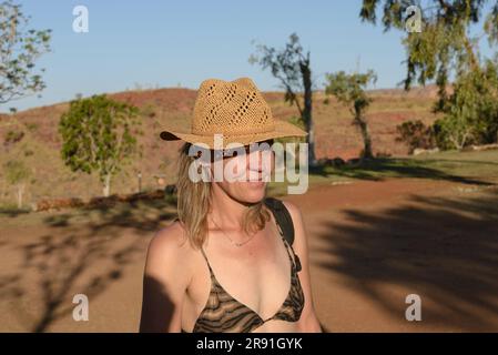 Eine Frau in einem Bikini und einem Strohhut genießt die Hitze im Outback in Australien Stockfoto