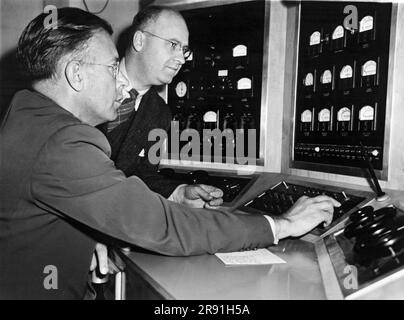 Berkeley, Kalifornien, 10. August 1945 Dr. Ernest Lawrence, Erfinder des Zyklotrons, und UC-Ingenieur WB Reynolds, untersuchen das Bedienfeld der 60-Zoll-Atompistole, die bei der Herstellung der ersten Atombombe verwendet wird. Stockfoto