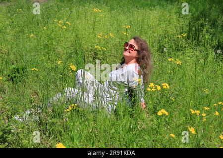 Das Foto wurde im Stadtpark der Stadt Odessa aufgenommen. Das Bild zeigt eine junge attraktive Frau, die die warmen Sonnenstrahlen des Frühlings, Sitti, genießt Stockfoto