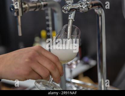 Prosecco-Sekt aus einem Hahn in eine Glasnaht gießen Stockfoto