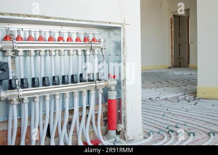 Montieren Sie die Systemverteilerbaugruppe der Fußbodenheizung zu Hause. Stockfoto