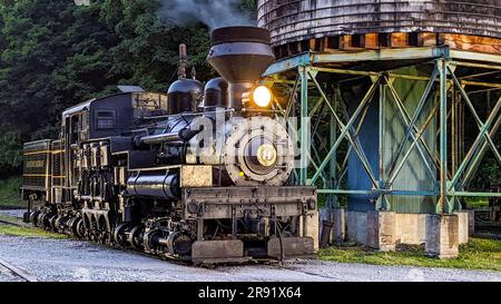 Cass, West Virginia, 18. Juni 2022 - Blick auf eine antike Shay Dampflok, die sich von einem alten Wasserturm erwärmt, der Rauch bläst Stockfoto