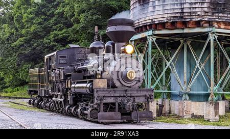 Cass, West Virginia, 18. Juni 2022 - Blick auf eine antike Shay Dampflok, die sich von einem alten Wasserturm erwärmt, der Rauch bläst Stockfoto