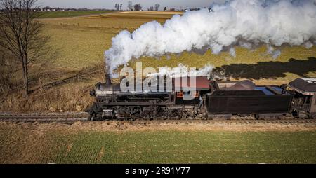 Ein restaurierter antiker Dampferzug, der an einem sonnigen Herbsttag durch die Landschaft reist, aus der Vogelperspektive Stockfoto