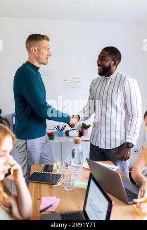 Geschäftsleute, die bei der Besprechung im Büro Handschlag machten Stockfoto
