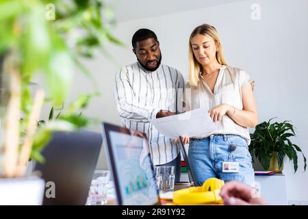 Multiethnische Kollegen diskutieren über Papierdokumente im Büro Stockfoto