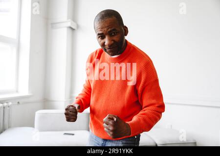 Selbstbewusster reifer Mann, der zu Hause die Faust zusammendrückt Stockfoto