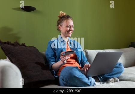 Glückliche junge Frau, die zu Hause online einkauft Stockfoto