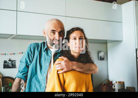 Ein reifes Paar, das zuhause in der Küche zusammensteht Stockfoto